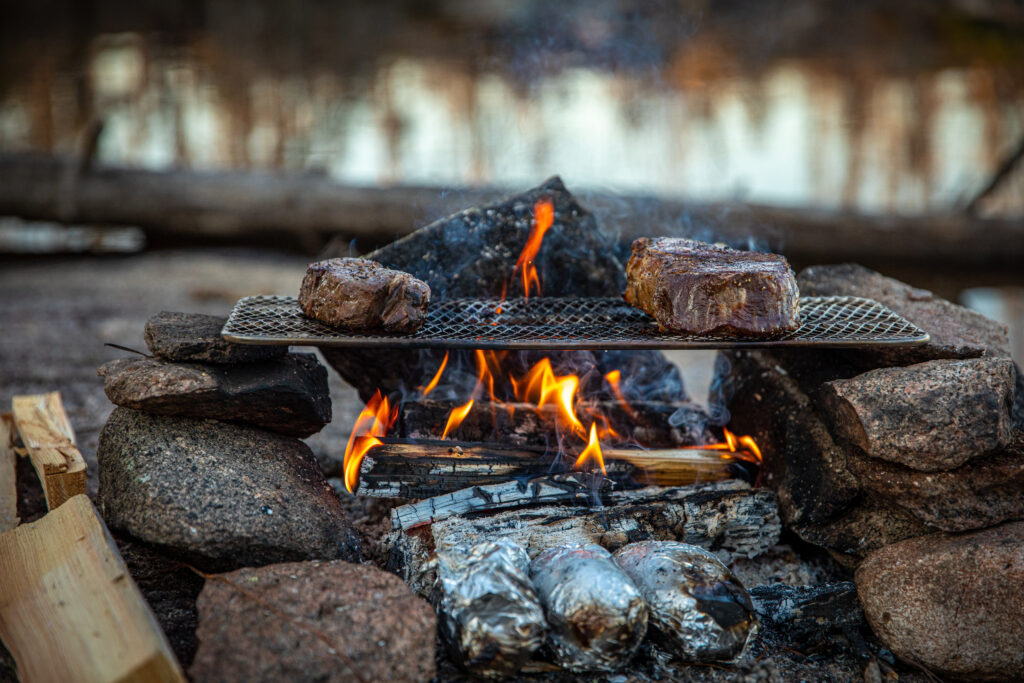 Cooking a ribeye over an open fire while camping