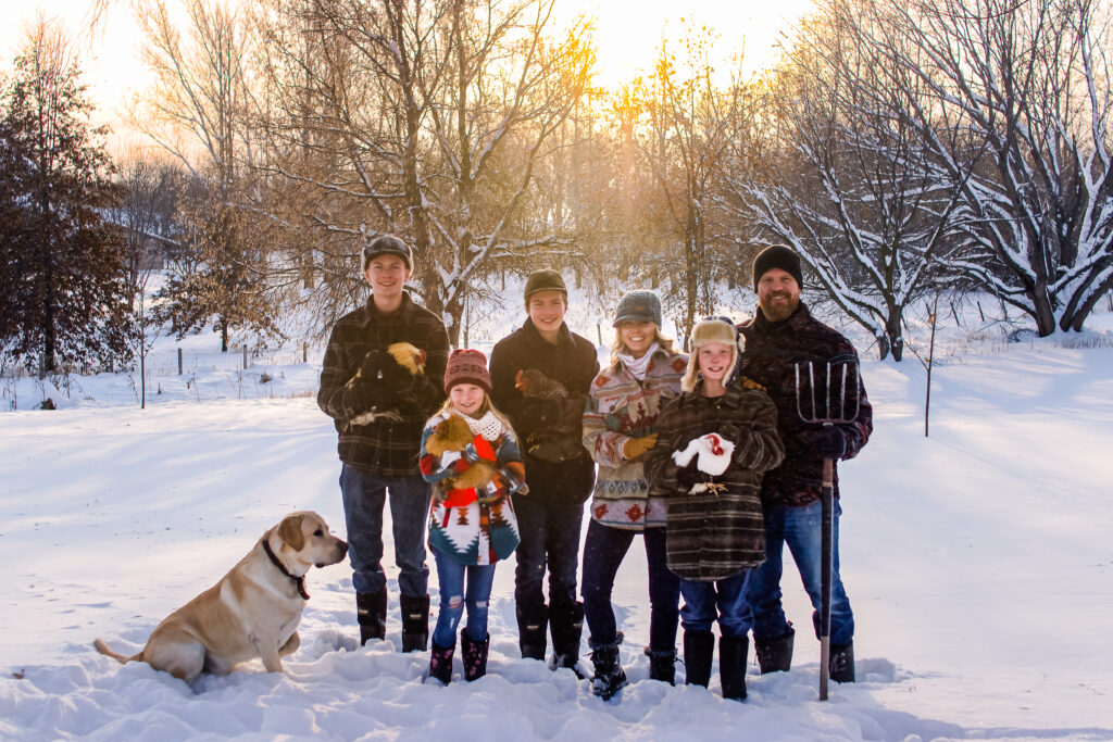 Heidi smiles with her family in a snowy field (@withheidijoy).