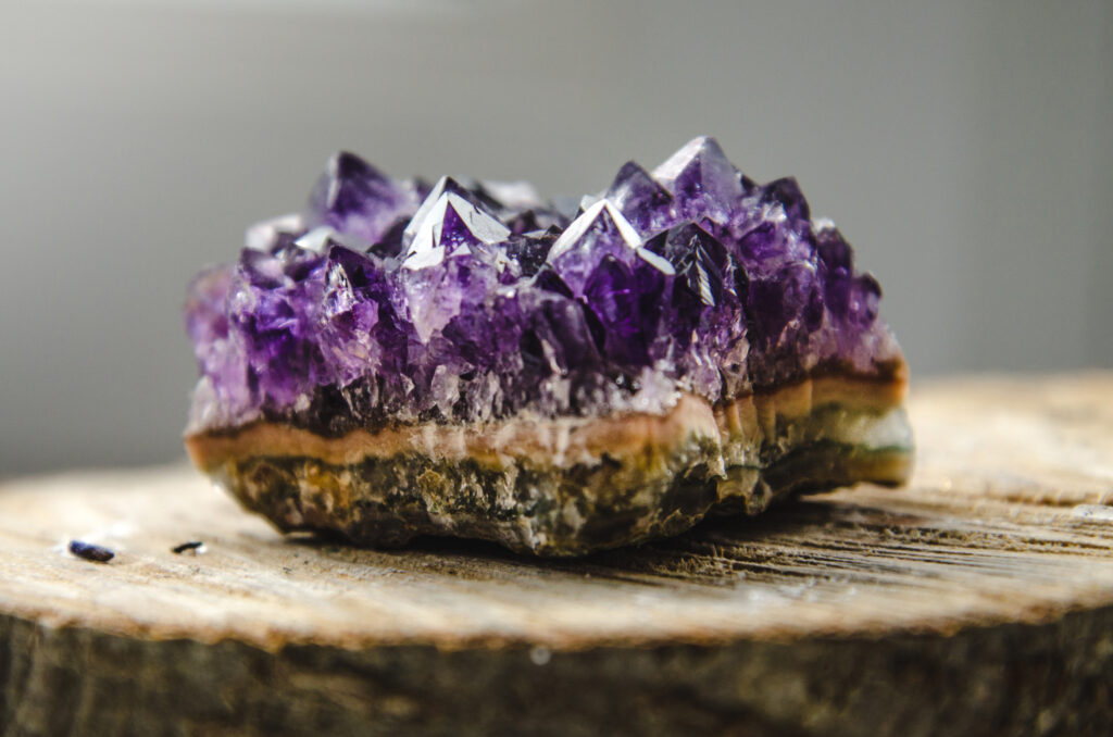 An amethyst stone sits on a stump.