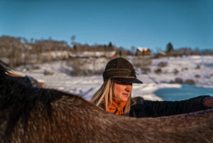 Anna Ciell stands at the side of her horse while outside.