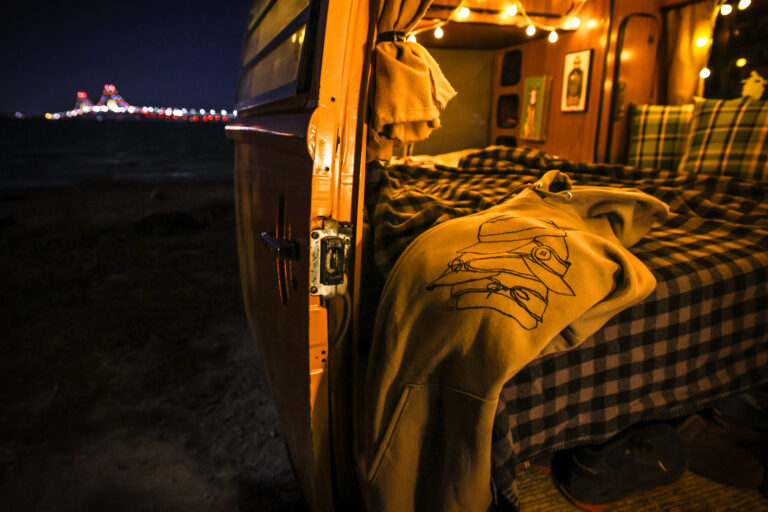 a Stormy Kromer hoodie laying on a bed in a campervan