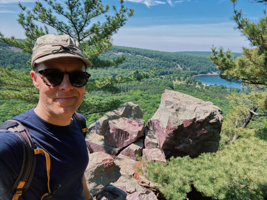 paul wheatley standing on the cliffside, in the mountains