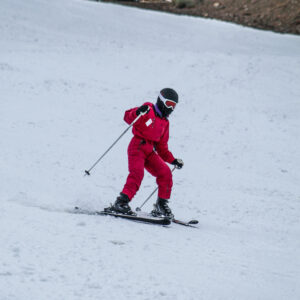 a skier in a red snowsuit going downhill