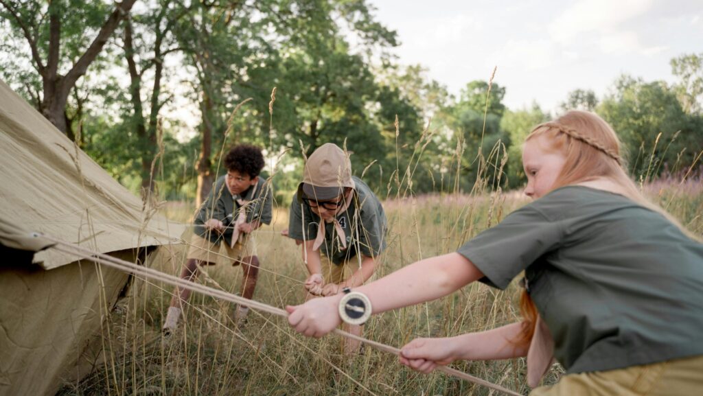 kids at a campsite, helping set up a tent