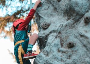 A young man bouldering up the side of a cliff