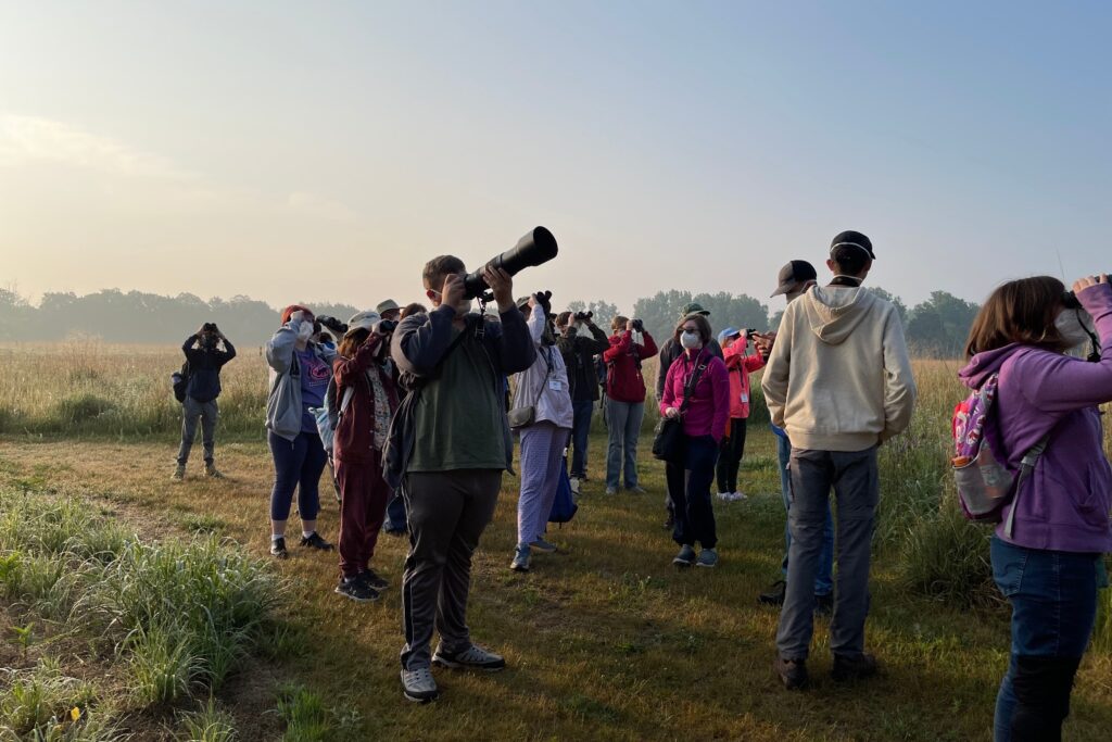 Campers at Chippewa look through cameras and binoculars for birds.